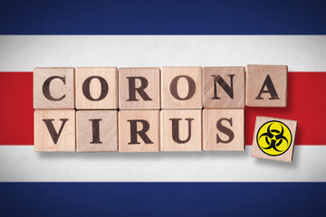 Costa Rica flag background and wooden blocks with letters spelling CORONAVIRUS and quarantine symbol on it. Novel Coronavirus (2019-nCoV) concept, for an outbreak occurs in Costa Rica.