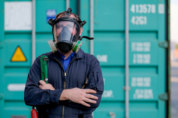 Technician or worker with chemical mask also engineer uniform stand and hold wrench in front of...