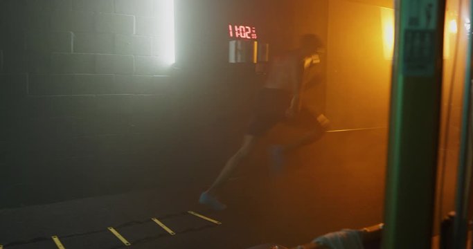 Man doing agility workout in dark gym