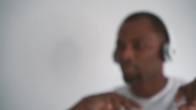 Attractive cuban man moving his body dancing with bluetooth headphones. Indoors music and dance concept. Urban style person isolated on white background. Hands on and off focus movement.