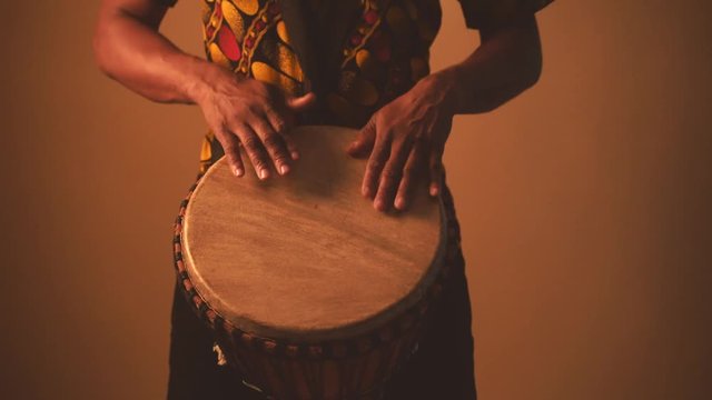 Detail of african american man musician playing traditional drums at brown background. Online musical class. Leisure learning musical instruments. Rhythm and blues style. Ethnic traditions.