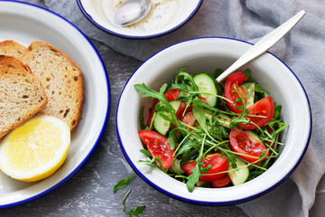 Salad with arugula, tomatoes, cucumbers and lemon sauce.
