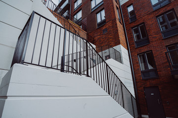White staircase in a modern block of flats. Building made of red bricks.