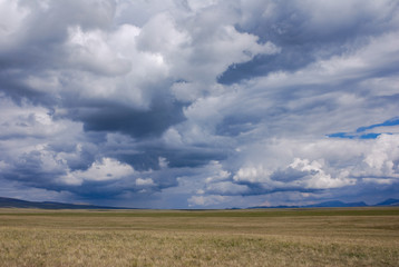 Obraz premium Vast Kyrgyz steppe, near Songkol lake. Dramatic sky with epic clouds. Kyrgyzstan.