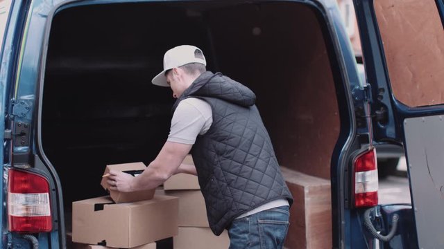 Delivery man at van scanning boxes with barcode scanner