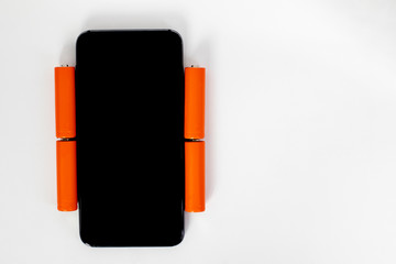 Mobile phone charging concept. Smartphone and orange batteries