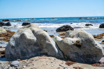 big rock on beach with ocean behind