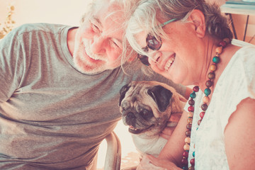 Funny happy portrait with two senior people man and woman with fun pug dog in the middle - love for...
