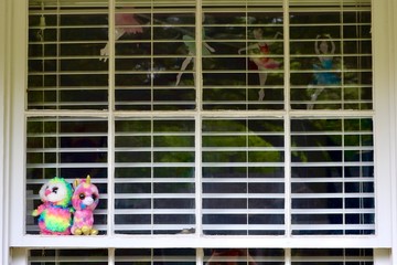 Stuffed animals in window with blinds for neighborhood scavenger hunt during corona virus outbreak