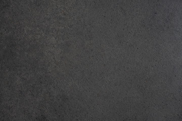 Gray-black granite countertop texture. Black background with splashes of shiny pebbles..