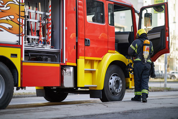 Fireman in uniform in front of fire truck going to rescue and protect. Emergancy servise concept.