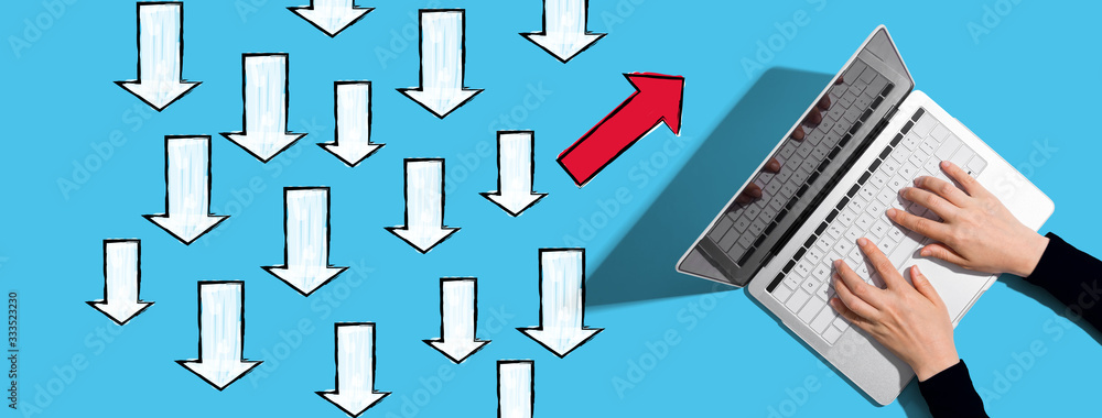 Poster arrow going in a different direction with person using a laptop computer
