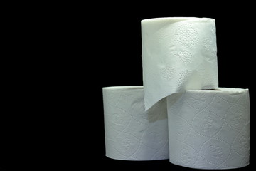 A color image of three rolls of white toilet paper with a black background.
