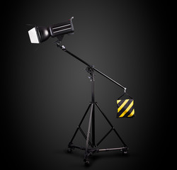 Photography studio flash on a lighting stand isolated on black background.