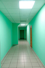 Hospital corridor with false ceiling, green walls and tiled floor