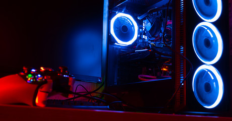 Glass pc case with blue lighting with a game pad on the foreground