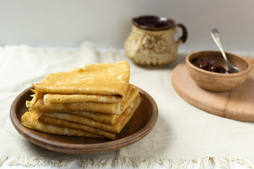 Pancakes (Russian Blini) with strawberry jam and tea in a rustic style. Breakfast. Сlose up.