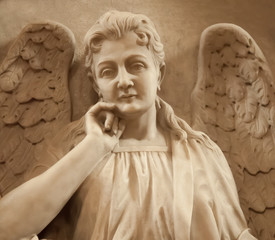Close up of beautiful angel with wings. Ancient stone statue, fragment.
