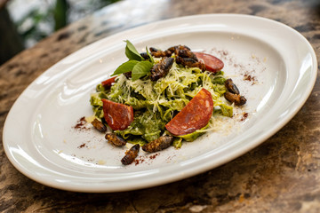 green spaguetti dish with insects and salami