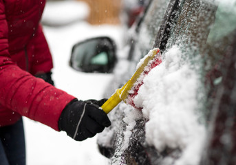 woman cleaning her car from snow