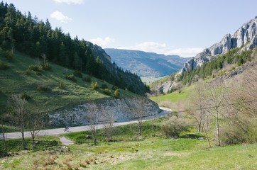 Fototapeta na wymiar Small cyclist in distance on huge mountain road
