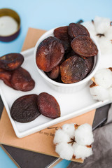 Dark chocolate dried apricots in a white plate on a blue background