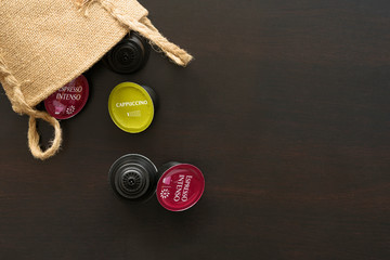 Coffee arrangement - scattered capsules for coffee machine. Dark background table. Jute bag.