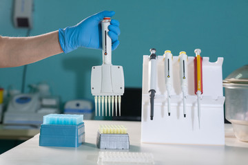 Medical test lab. Hand in glove with automatic multichannel pipette for pcr analysis of nucleic...