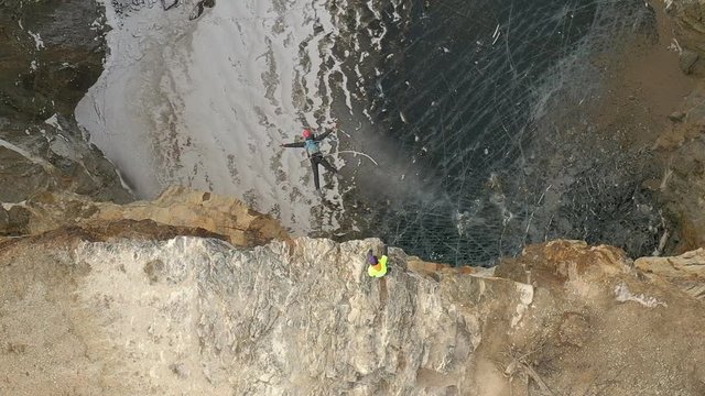 Top view of a brave man jumps into the Tuimsky sinkhole on a bungee.