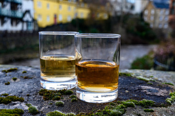 Scotch single malts or blended whisky spirits in glasses with old houses of Edinburgh on background, Scotland, UK
