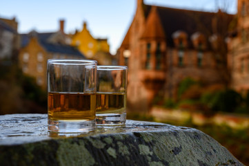 Scotch single malts or blended whisky spirits in glasses with old houses of Edinburgh on...