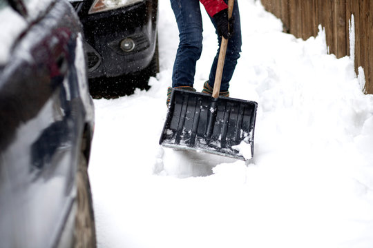 woman in red jacket with shovel cleaning snow. Winter shoveling. Removing snow after blizzard