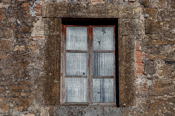 Fototapeta na wymiar Antigua ventana de de madera vieja con cristales traslúcidos y pared de piedra