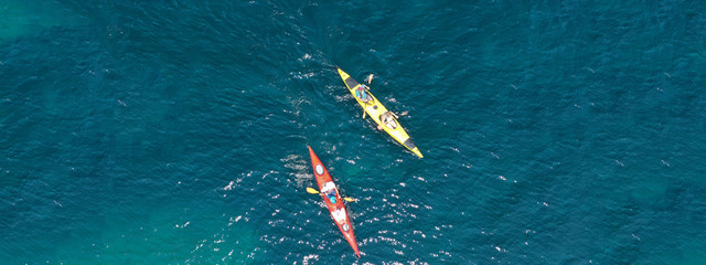 Aerial drone ultra wide photo of young couple canoeing in tropical exotic island bay