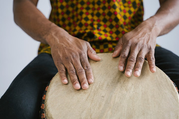 Detail of african american man musician playing traditional drums at home. Online music class concept. Leisure learning musical instruments. Rhythm and blues style. Ethnic multicultural traditions.