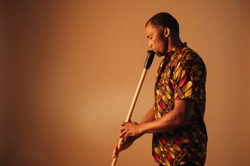 African american man musician playing the flute at brown background copy space. Online musical class learning musical instruments. Rhythm and blues style. Ethnic culture and traditions. © beavera