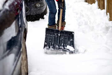 woman in red jacket with shovel cleaning snow. Winter shoveling. Removing snow after blizzard
