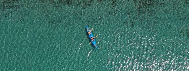 Aerial drone ultra wide photo of young couple canoeing in tropical exotic island bay