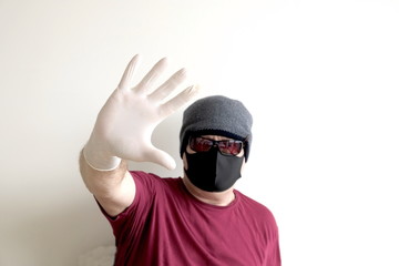 Portrait of a man protected from coronavirus. White, latex gloves. Hand protection against infections, viruses, germs. Isolation of the skin. On the face is a fabric mask. Glasses on the eyes. Symboli
