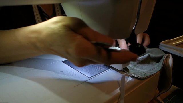 A tailor sews a medical mask at home to protect against coronavirus