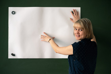 Teacher is showing a blank whatman paper with copy space on a chalkboard background.