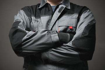 Worker in the robe is standing with crossed arms close up on gray background.