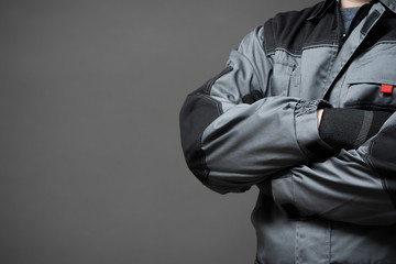 Worker in the robe is standing with crossed arms close up on gray background.