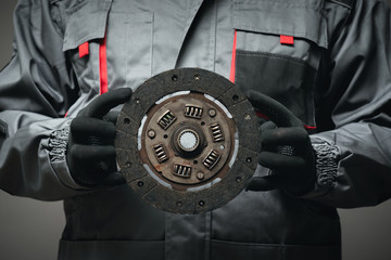 A car mechanic is showing an old car clutch disk close up.