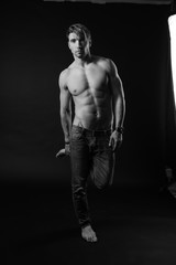 Fototapeta na wymiar black and white studio shoot of strong athletic man on dark background. sexy body