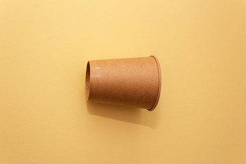 One craft paper cup for coffee or any drinks on a  yellow paper background. Concept of ziro waste, no plastic
