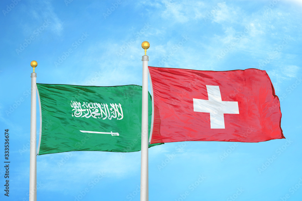 Wall mural saudi arabia and switzerland two flags on flagpoles and blue cloudy sky