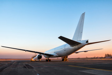 Plakat White wide body passenger aircraft at the airport apron in the evening light