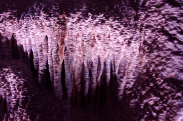 rock stalactites on rock wall in dark tunnel