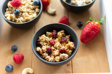 Müsli im Schälchen mit getrockneten Früchten auf einem Holztablett. In Nahaufnahme